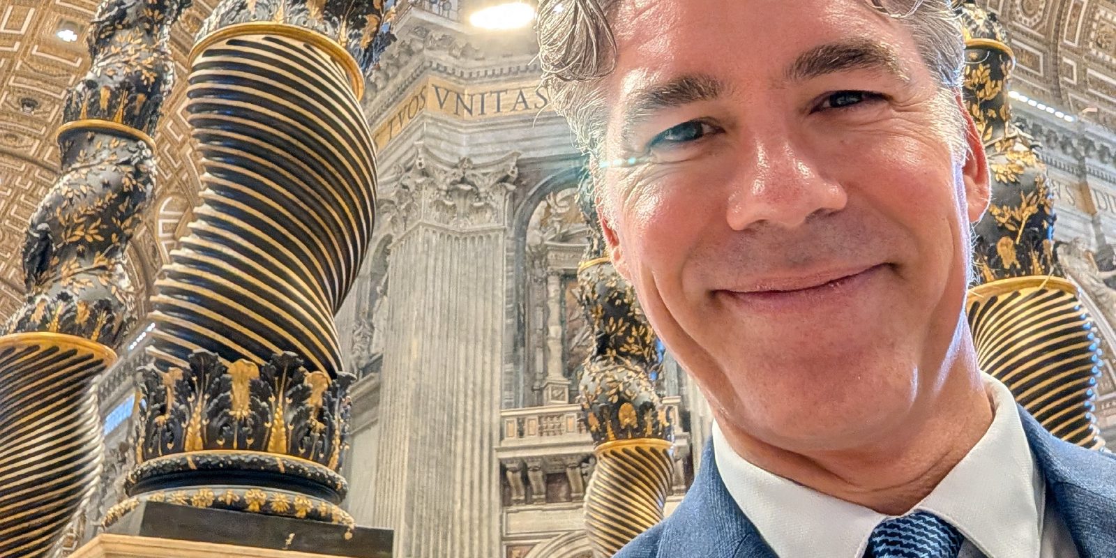 Damien Riehl at the Vatican, the ornate interior of St. Peter's Basilica behind him.